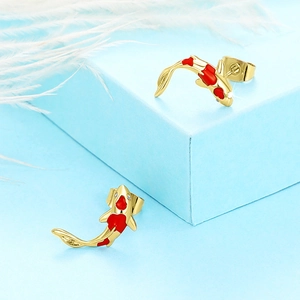 Detail of gold koi fish earrings with red enamel spots and zircon inlay on blue display