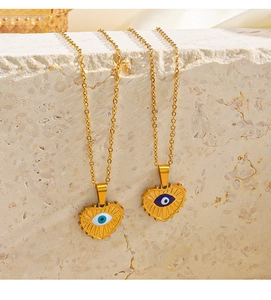 Detail of gold heart necklaces with blue evil eye pendants on stone texture