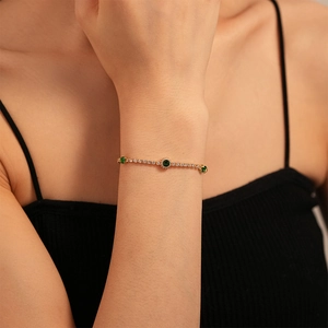 Close-up of gold plated tennis bracelet featuring sparkling green zircon gemstones on wrist