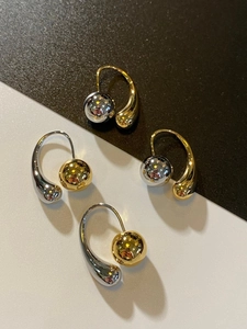 Close-up of French vintage teardrop earrings with gold and silver metal spheres