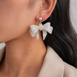 Close-up of sparkling bow knot earrings with diamonds on model showing elegant detail