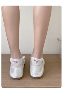 Detail view of white low cut socks featuring a delicate pink embroidered bow on the heel