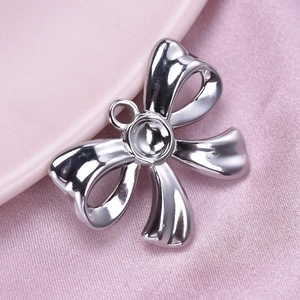 Macro view of silver bow-knot pendant on pink silk fabric showing metallic details