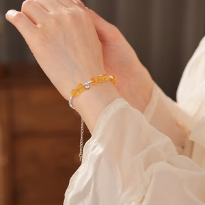 Close-up of a citrine bead bracelet with silver charms on a woman's wrist