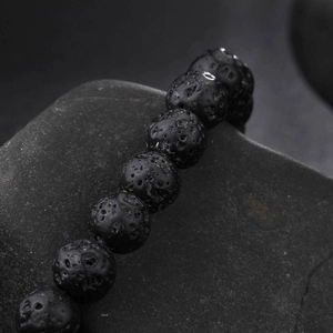 Vue macro de perles en pierre de lave noire mate sur un fond de roche naturelle assorti