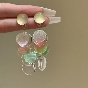 Macro detail of translucent shell-like resin tassels on beach style drop earrings
