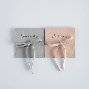 Detail view of square microfiber suede jewelry pouches in grey and peach colors.