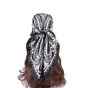 Detail of black paisley satin scarf tied as a headband on long brown hair