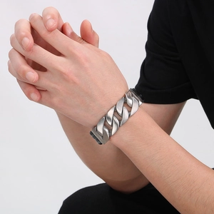 Close-up of a silver stainless steel Cuban chain leather bracelet on a male wrist