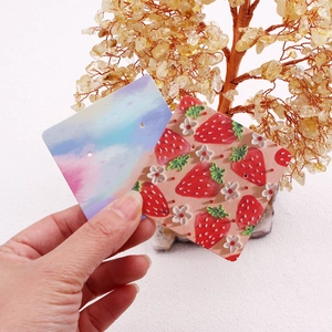 Floral and colorful cloud earring display cards held by hand against a crystal tree