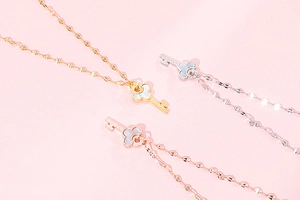 Three key-shaped necklaces in gold, silver, and rose gold with white clover inlays