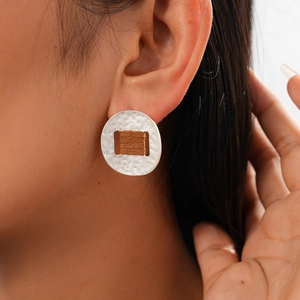 Detail of silver textured hoop earring with brown fabric detail worn on the ear