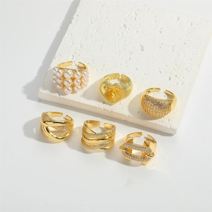 Detailed view of luxury gold rings with micro-pave crystals and pearl accents on white marble