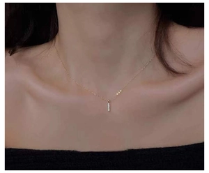 Detail of 14k gold plated bar necklace with sparkling zircons on elegant model neckline