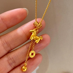 Detail of 24K gold-plated pony and coin pendant necklace with polished metal texture