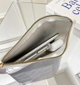 Interior view of white crocodile pattern clutch bag showing phone and earphone storage