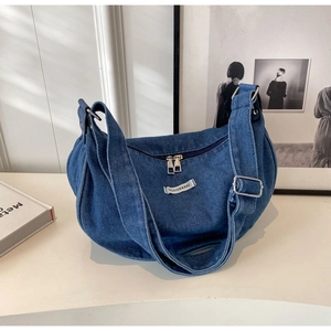 Detailed close-up of dark denim hobo crossbody bag featuring white fashion label and metal zipper