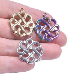 Detailed shot of three witch knot pendants in gold, silver, and rainbow on a palm