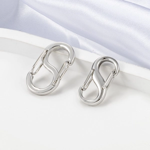 Macro view of silver S-shape stainless steel connector clasps on white silk background