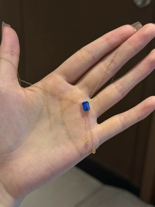 Vue détaillée du collier doré avec pierre précieuse bleue rectangulaire et deux petits anneaux