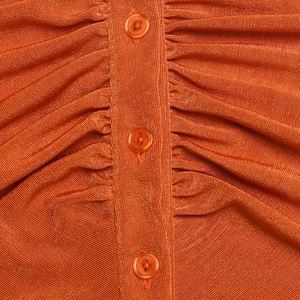 Vista macro del tessuto a maglia arancione con tre bottoni coordinati sul top senza maniche