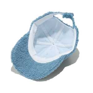 Detail view of the warm lamb wool lining and internal stitching of the blue baseball cap