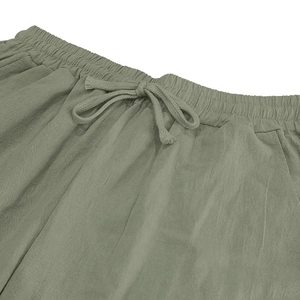 Dettaglio dei pantaloni in lino grigio-verde con vita elastica e coulisse regolabile