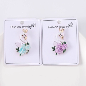 Detail of swan earrings with blue and purple roses on white jewelry cards