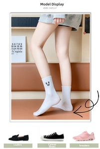 Close-up of white cotton socks featuring a dollar sign smiley face embroidery detail