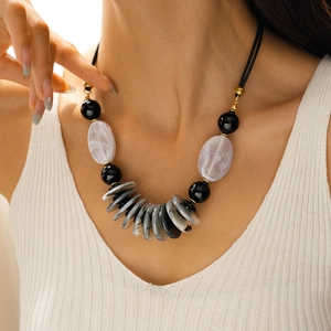 Detail of beaded leather necklace with oval acrylic pendant on model collarbone