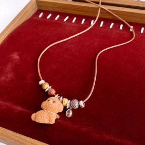 Detail of flocked puppy pendant necklace with wooden beads and crystal drop on velvet