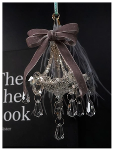 Chandelier ornament with faceted crystal, gray velvet bow and feathers on black background