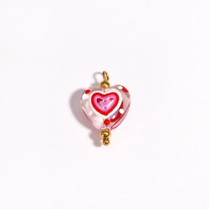 Close-up of pink heart-shaped glass bead with red inner heart and gold accents