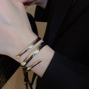 Close-up of a wide multi-layer spiral gold bangle with high-polished metallic finish
