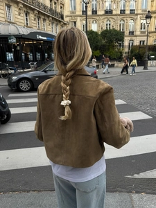 Rear view of women's brown suede button jacket on a street in a casual city setting