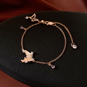 Detail of gold butterfly bracelet with purple teardrop gems and zircon stones on green pad