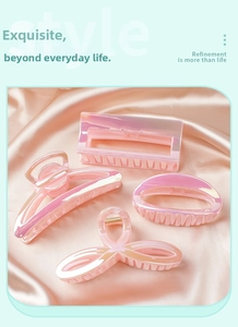 Close-up of four iridescent pink hair clips on a soft pink silk background