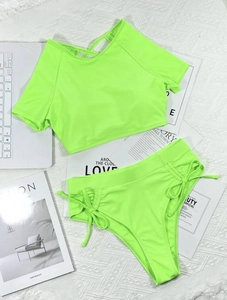 Detail of neon green high-waisted bikini with side drawstrings and cropped short sleeve top