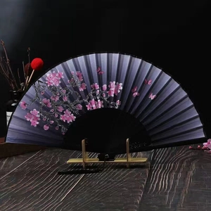 Detailed view of silk folding fan with pink cherry blossoms and butterfly pattern