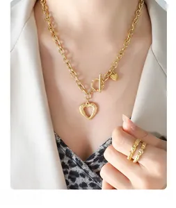 Macro detail of gold chunky chain necklace with heart pendant and textured rings