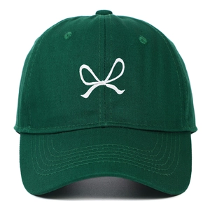Detail of white bow embroidery on deep green cotton baseball cap with twill texture