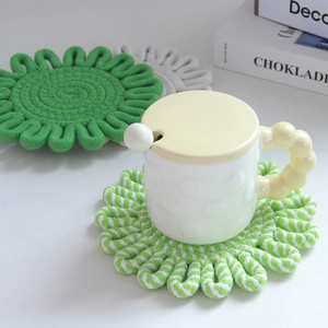 Close-up of flower-shaped woven cotton heat-resistant coasters in green and white colors