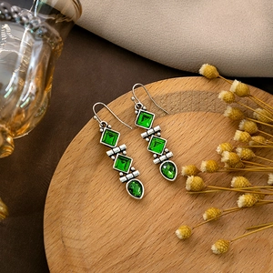 Close-up of vintage silver bohemian earrings with emerald green tiered square and pear gems