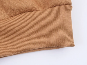 Gros plan sur la veste en daim camel avec poignets en maille côtelée et coutures fines