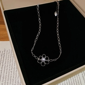 Detailed shot of silver hollow flower necklace with round pearl in black velvet box