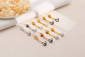 Detail view of pearl drop earrings in gold and silver finishes on a textured surface