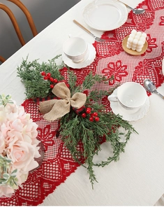 Detailed view of red lace Christmas table runner with tassels and hollow pattern on table