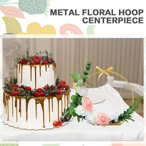 Detail of a metal floral hoop centerpiece with pink roses on a wooden base for wedding decor