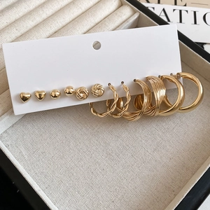 Detail view of 6 pairs of gold-plated stud and hoop earrings set on a white card display
