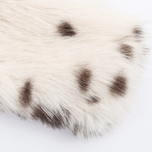 Close-up of faux fur texture with dark brown spots on an off-white animal print coat
